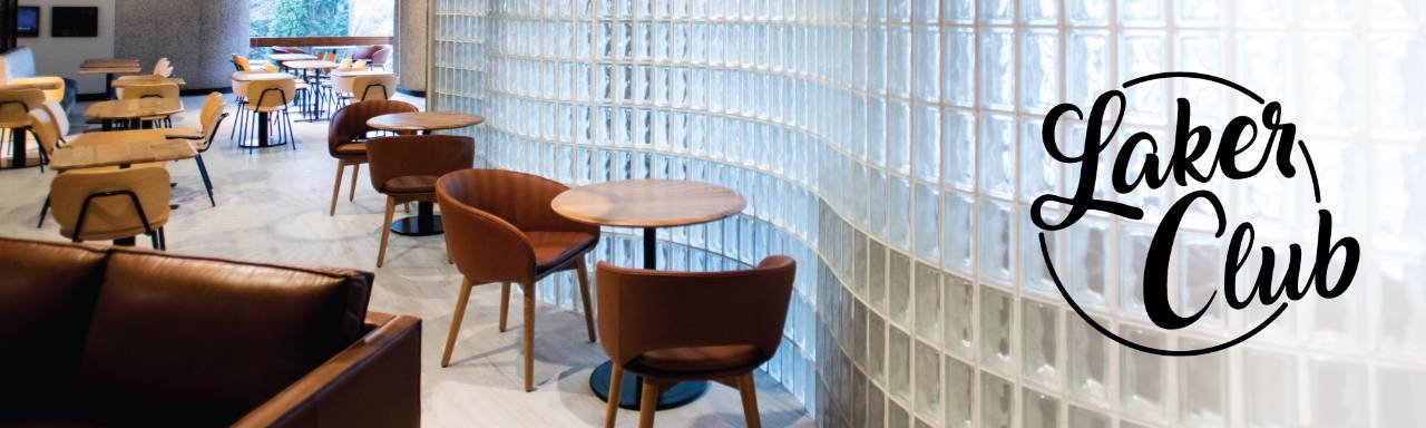 Interior of Laker Club, a curved glass brick wall next to brown chairs and tables
